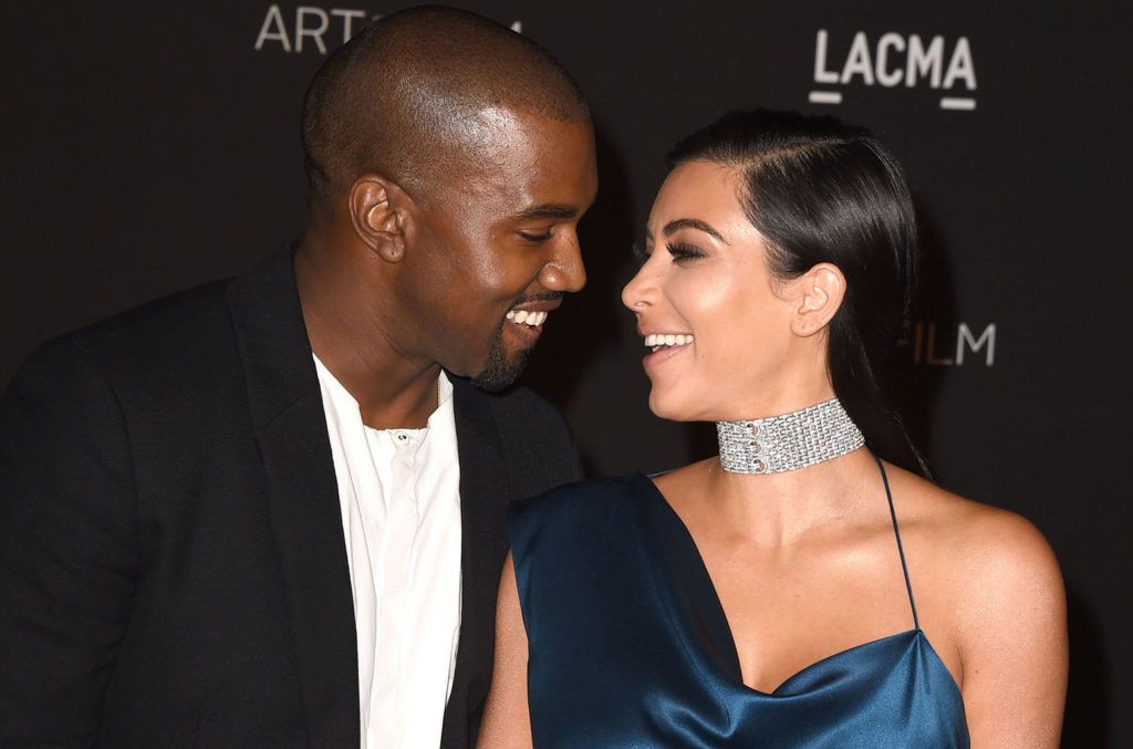 Kanye West and Kim Kardashian looking at each other and laughing happily on a red carpet