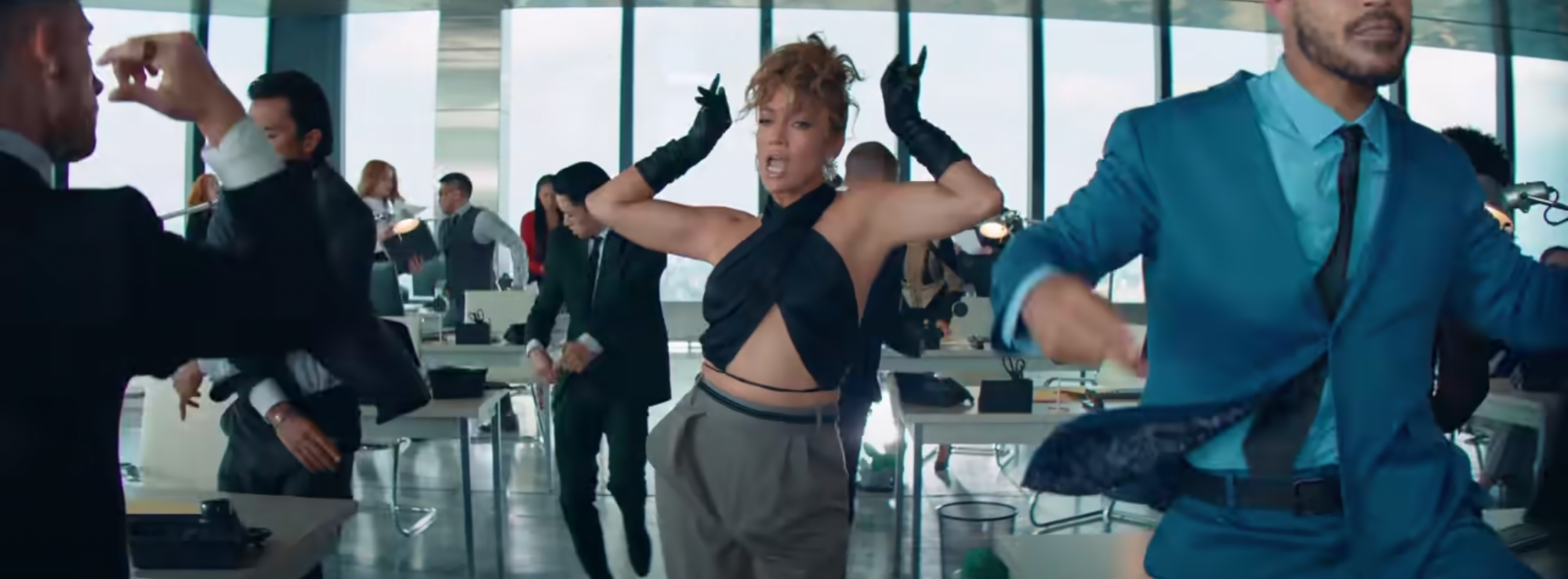 image of J.Lo in the office in a midriff-revealing halter top and leather gloves